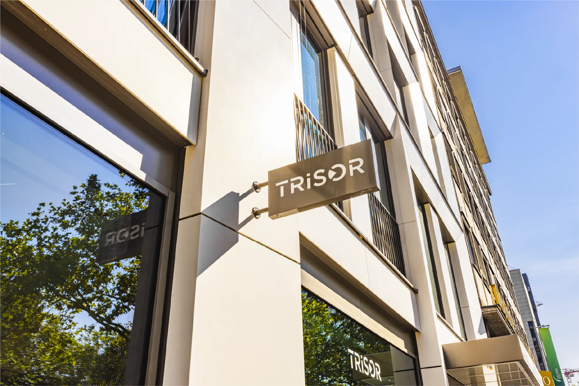 Außenfassade eines modernen Stadtgebäudes mit dem beleuchteten Trisor-Schriftzug