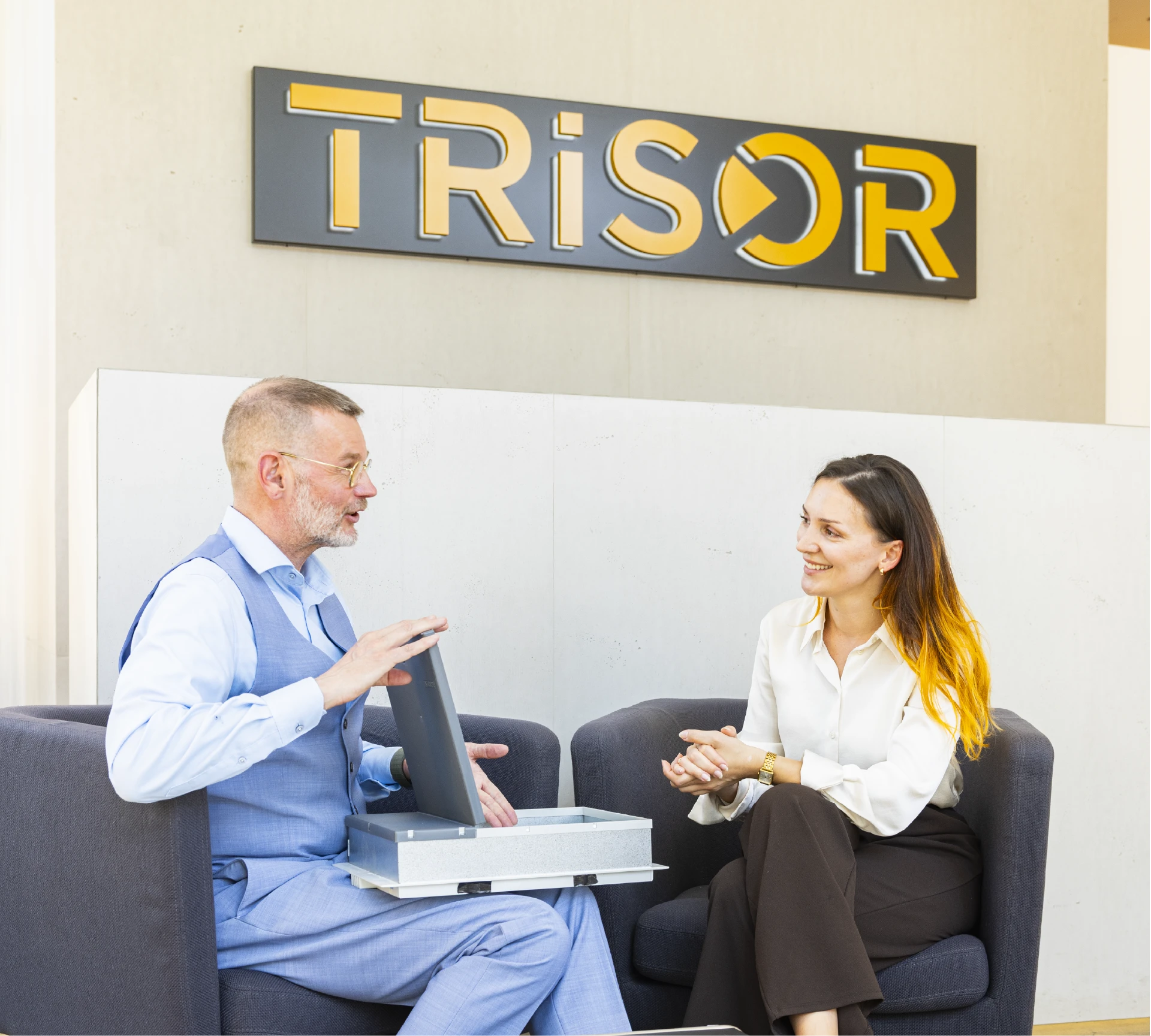 Trisor danışmanı ve müşteri Berlin'deki oturma alanında oturuyor, aralarında açık ve boş bir kiralık kasa var