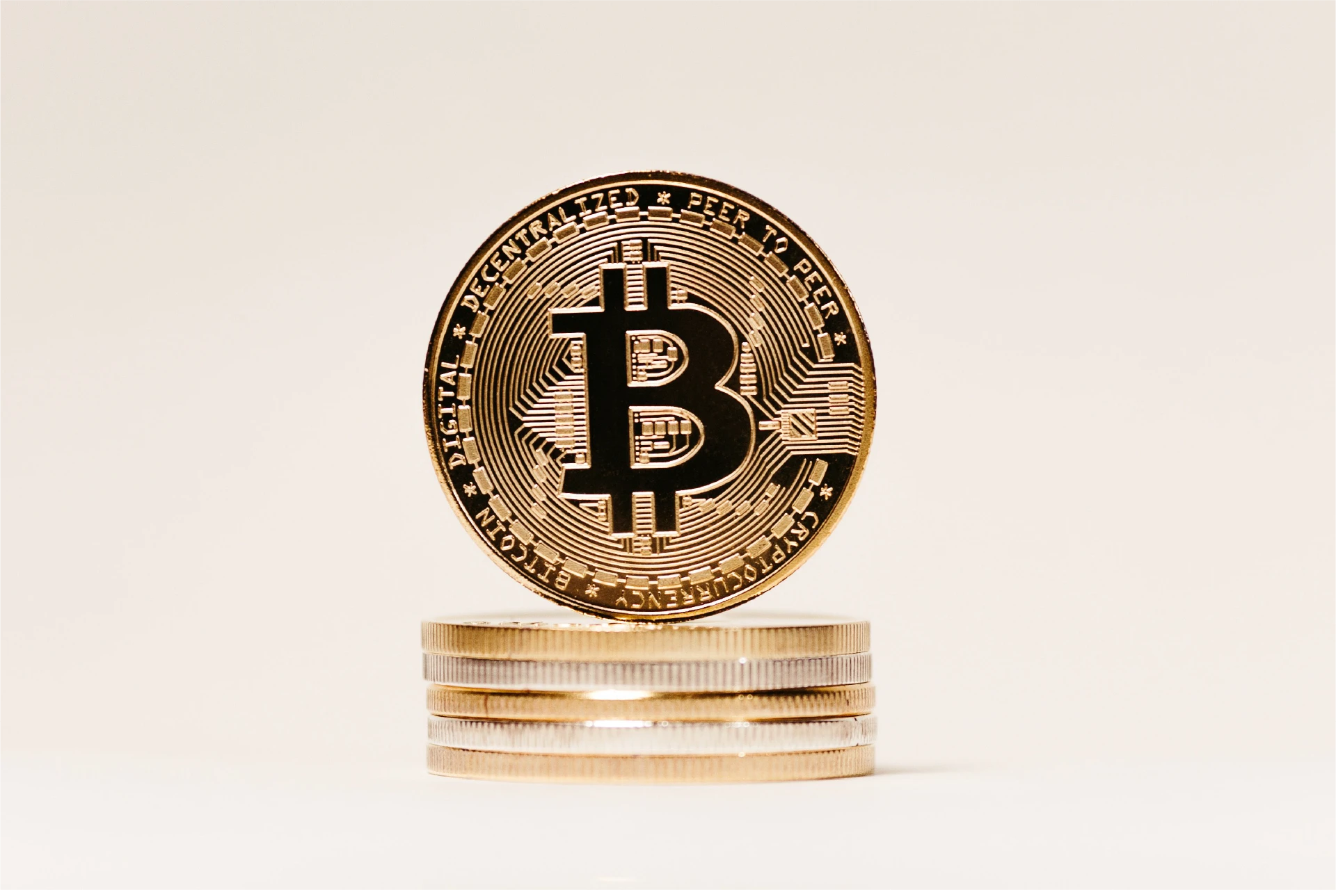 Physische Bitcoin-Münze auf einem Stapel Münzen vor hellem Hintergrund
