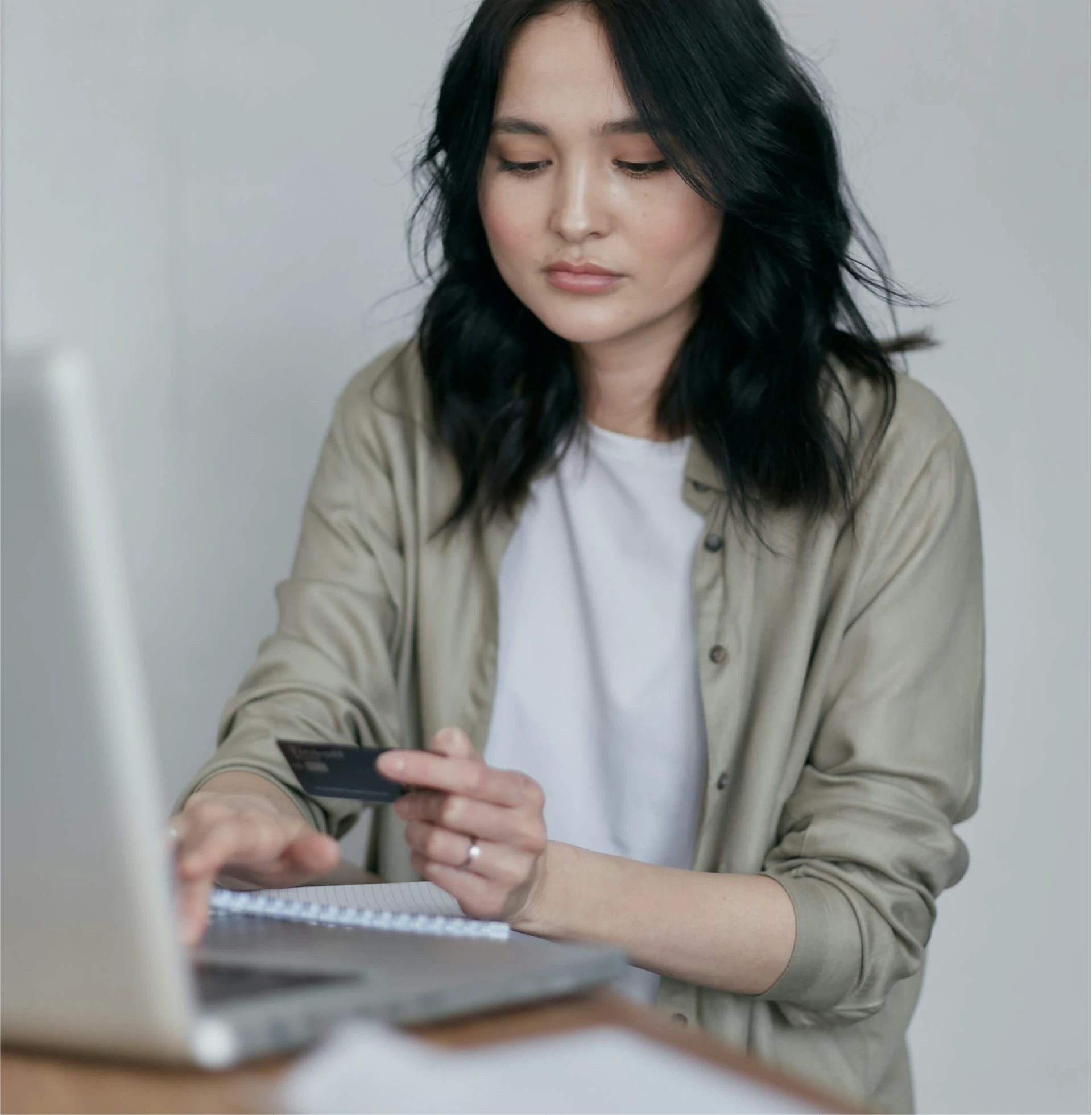 Woman doing online banking on a laptop with a credit card in hand