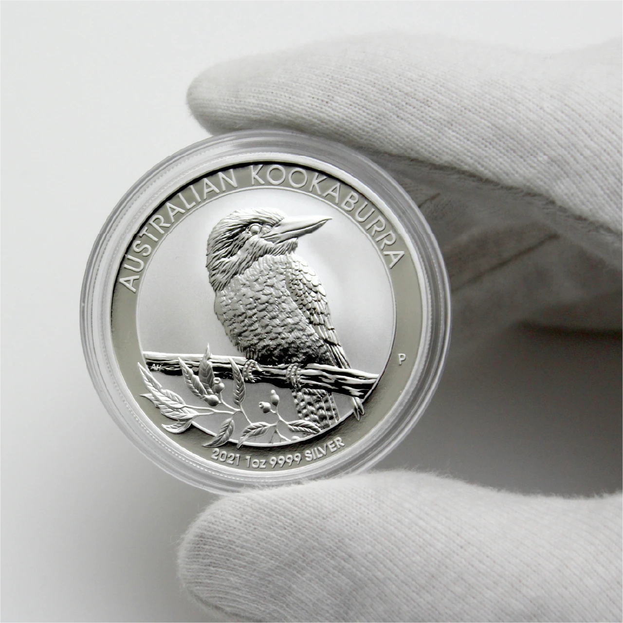 Silver coin with bird motif in a gloved hand